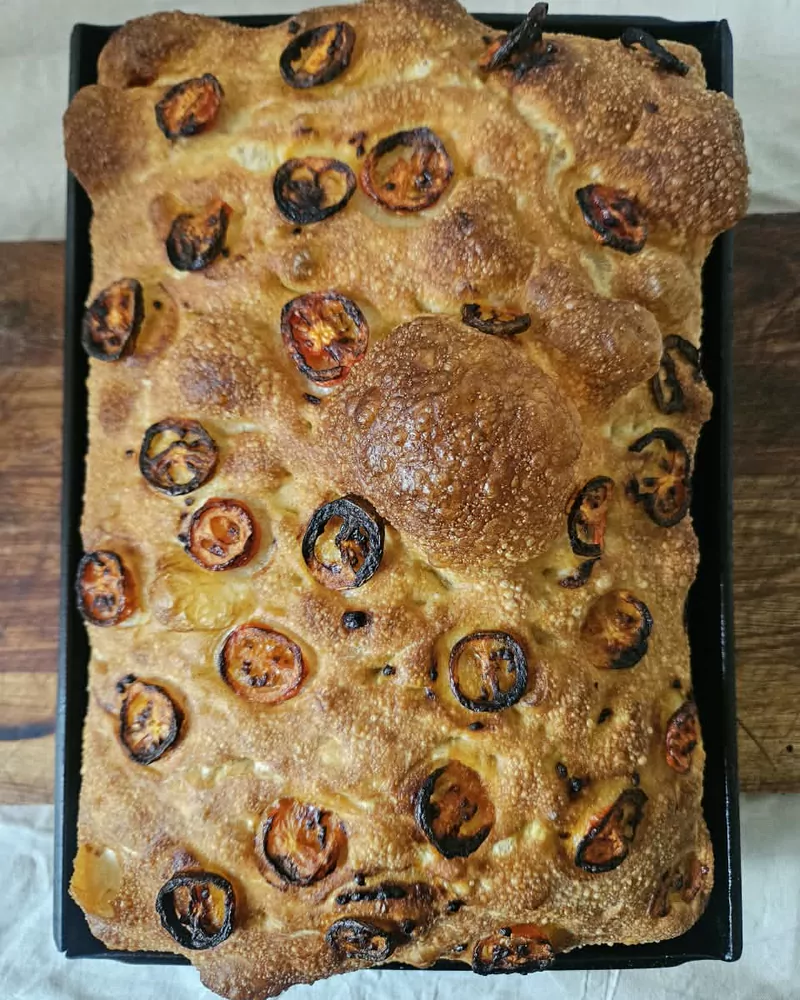 Focaccia artesanal con tomates asados recién salida del horno en bandeja, Bona Biga Pan Mendoza