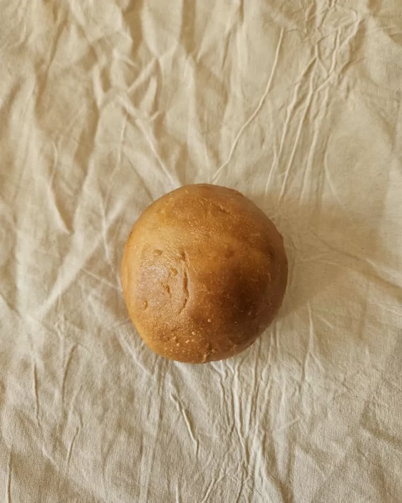Pan de hamburguesa artesanal dorado sobre lino crudo, Bona Biga Pan Mendoza
